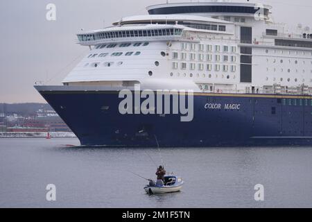 12 dicembre 2022, Schleswig-Holstein, Kiel: Un pescatore sta pescando sul fiordo di Kiel mentre il traghetto della linea di colore lo passa per il Mar Baltico. Foto: Marcus Brandt/dpa Foto Stock