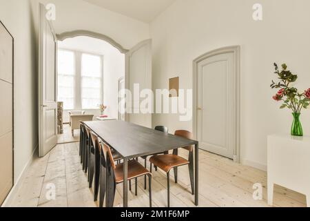 Semplice tavolo con sedie situato sotto un elegante lampadario vicino alle porte in un'elegante sala da pranzo Foto Stock