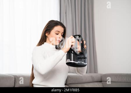 Una giovane donna indossa una cuffia per la realtà virtuale nel salotto di casa. La tecnologia del concetto futuro. Foto Stock