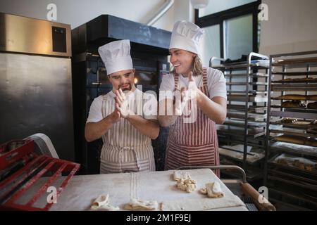 Uomo con giù sindromi aiutare a preabbinare il pane in panetteria con il suo collega. Concetto di integrazione delle persone con disabilità nella società. Foto Stock