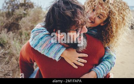 Un uomo trasporta la donna overjoyed in piggyback in attività di svago all'aperto insieme avendo divertimento e ridendo mólto. Felice gente matura giovani dentro godere Foto Stock