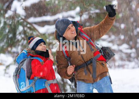 Escursioni invernali - padre e figlio durante una videochiamata online in una foresta innevata. Foto Stock