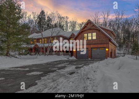 Una bella casa in legno contemporaneo rustico nelle montagne innevate di sera Foto Stock