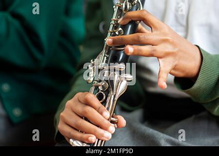 Primo piano delle mani dell'allievo della scuola che gioca il clarinetto Foto Stock