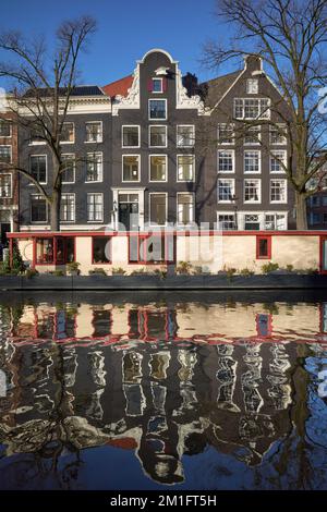 Una vista che guarda ad Est sul canale Prinsengracht che mostra una casa galleggiante ormeggiata di fronte ad una fila di case tradizionali di Amsterdam. Foto Stock