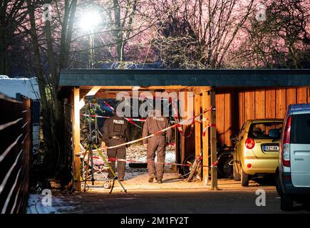 12 dicembre 2022, Schleswig-Holstein, Alt Mölln: Investigatori di polizia si trovano dietro un edificio di appartamenti all'ingresso di un giardino. Un corpo sepolto è stato trovato lì in un buco nel terreno a mezzogiorno. Foto: Daniel Bockwoldt/dpa Foto Stock