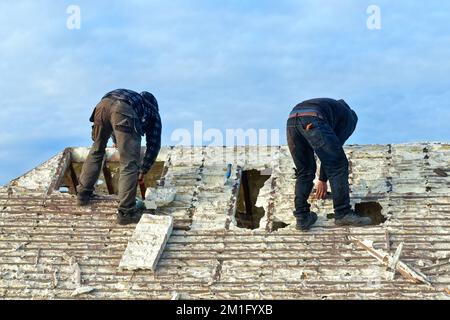 Costruttori che rimuovono l'isolamento in schiuma spray indurita dallo spazio sul tetto di una casa privata suburbana, Shepperton Surrey Inghilterra UK Foto Stock