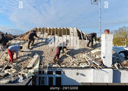 Costruttori che rimuovono l'isolamento in schiuma spray indurita dallo spazio sul tetto di una casa privata suburbana, Shepperton Surrey Inghilterra UK Foto Stock