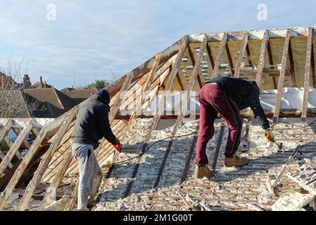 Costruttori che rimuovono l'isolamento in schiuma spray indurita dallo spazio sul tetto di una casa privata suburbana, Shepperton Surrey Inghilterra UK Foto Stock