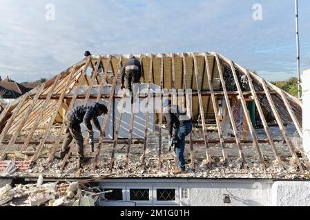 Costruttori che rimuovono screditato spray espanso isolamento dallo spazio del tetto di una casa privata suburbana, Shepperton Surrey Inghilterra UK Foto Stock