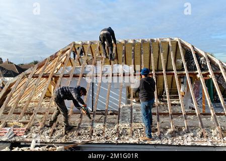 Costruttori che rimuovono screditato spray espanso isolamento dallo spazio del tetto di una casa privata suburbana, Shepperton Surrey Inghilterra UK Foto Stock