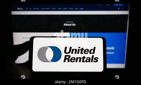 Persona che tiene in mano uno smartphone con il logo della società di noleggio attrezzature USA United Rentals Inc. Sullo schermo di fronte al sito Web. Messa a fuoco sul display del telefono. Foto Stock