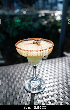 Una margarita gialla piccante con bordo guarnito e limone in un ristorante cocktail bar all'aperto Foto Stock