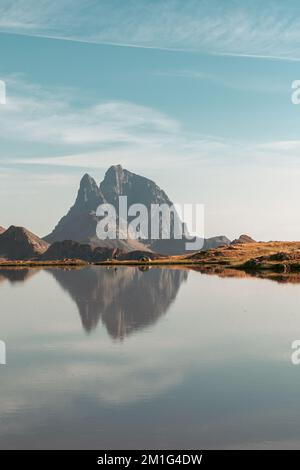 Un colpo verticale di Pic du Midi d'Ossau cima montagna con riflessione su un lago Foto Stock