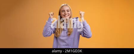 Trionfando festeggiando positivo capelli leale giovane vincitrice sollevare mani clench fists up vittoria risultato gesto vicino occhi sorridenti ampiamente Foto Stock