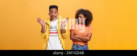 Jeez uomo che il vostro problema. Offeso dispiaciuto afroamericano elegante e attraente ragazza che guarda il ragazzo comportandosi cool fingendo lui Foto Stock