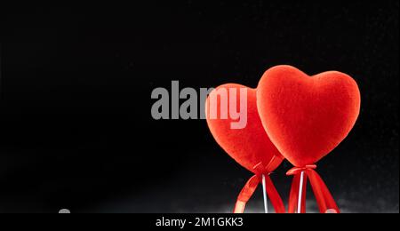 San Valentino, due cuori amorosi rossi su sfondo nero, banner con posto per il testo. Foto Stock
