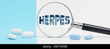 Medicina e concetto di salute. Su uno sfondo blu e bianco, ci sono pillole e una lente d'ingrandimento, all'interno della quale è scritto - HERPES Foto Stock