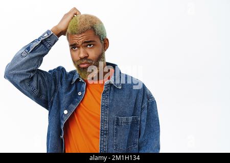 Primo piano della testa di graffio dell'uomo nero confuso, perplesso, sguardo clueless, levandosi in piedi sopra lo sfondo bianco dello studio Foto Stock