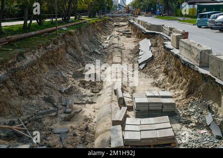 Lavori di costruzione per la posa di tubi di riscaldamento in una trincea. Il sistema di approvvigionamento di acqua fredda e calda negli edifici residenziali e nei locali industriali. Messa a terra Foto Stock