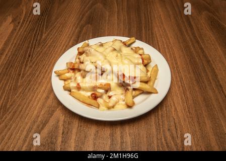 Una porzione di patatine fritte con un sacco di formaggio fuso con pancetta fritta e ketchup Foto Stock