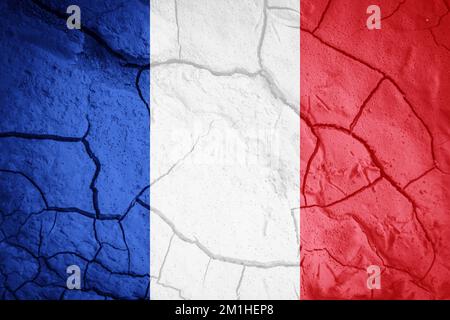 Bandiera della Francia. Simbolo francese. Bandiera sullo sfondo di terra secca spaccata. Bandiera francese con concetto di siccità Foto Stock