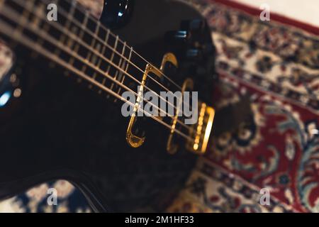 primo piano di una chitarra nera con corde dorate sul tappeto, concetto musicale. Foto di alta qualità Foto Stock