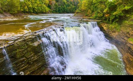 Aeree lungo il bordo di enorme cascata infuriante che si riversano sulle scogliere circondate da lussureggianti foreste verdi che si avvicinano alla caduta Foto Stock
