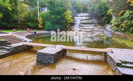 Enorme cascata terrazzata giù nel fiume con ponte pedonale e area salotto Foto Stock