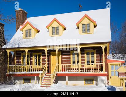 1978 costruito replica di vecchio giallo 1800s con finitura arancione canadiana cottage stile casa log in inverno. Foto Stock