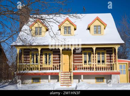 1978 costruito replica di vecchio giallo 1800s con finitura arancione canadiana cottage stile casa log in inverno. Foto Stock