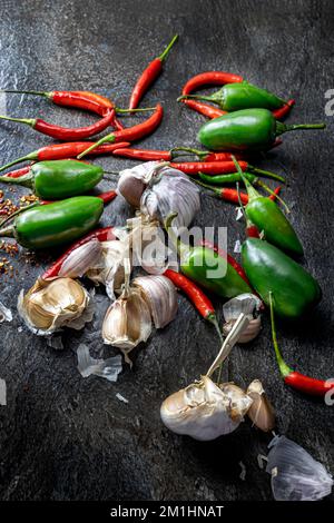 Peperoncini, peperoni, aglio e spezie su una panca da cucina Foto Stock