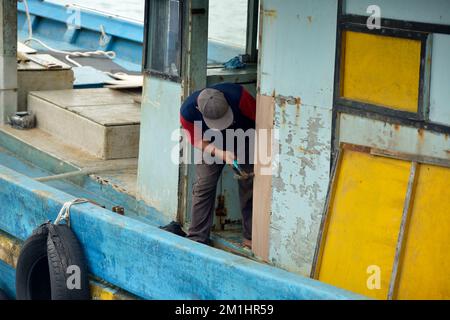 Un uomo indigeno Rungus che esegue lavori di manutenzione su una barca da pesca a Kudat, Sabah, Borneo, Malesia. Foto Stock