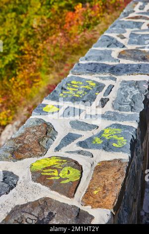 Mettere a fuoco lungo la parete di pietra con graffiti gialli stampe a mano ricordi di famiglia Foto Stock