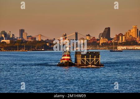 Piccola nave industriale che tira i contenitori di spedizione dal lato nell'ora d'oro industriale di New York City Foto Stock