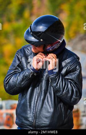 Ritratto verticale di motociclista sconosciuto indossando casco nero con bandiera americana e giacca in pelle nera Foto Stock