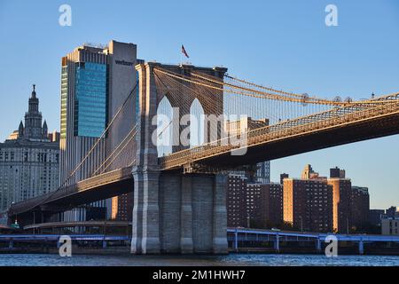 Splendido Ponte di Brooklyn a New York City con skyline sullo sfondo e bandiera americana Foto Stock