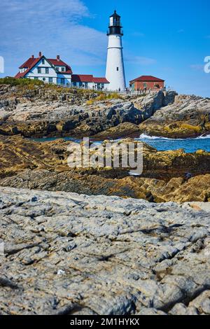 Enorme costa rocciosa in dettaglio con vista sul faro bianco Foto Stock