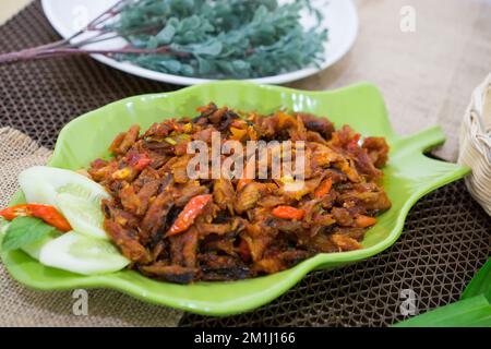 Pampis Tongkol/Cakalang, piatto di pesce tradizionale del Manado con pesce speziato, servito su un piatto verde Foto Stock