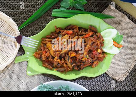 Pampis Tongkol/Cakalang, piatto di pesce tradizionale del Manado con pesce speziato, servito su un piatto verde Foto Stock