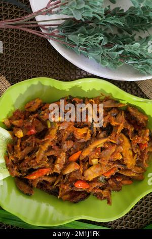 Pampis Tongkol/Cakalang, piatto di pesce tradizionale del Manado con pesce speziato, servito su un piatto verde Foto Stock