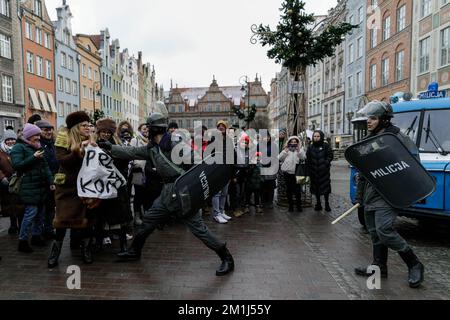 Gdansk, Polonia, 11/12/2022, uomini che indossavano un'uniforme della milizia della Repubblica popolare Polacca, che detenevano una donna che giocava un ruolo di dimostratore durante la performance di strada legata all'anniversario della legge marziale in Polonia, svoltasi sulla via Dluga nella Città Vecchia. Spettacolo di strada legato all'anniversario della legge marziale in Polonia, tenuto in una delle principali strade turistiche della Città Vecchia. La legge marziale in Polonia esisteva tra il 13 dicembre 1981 e il 22 luglio 1983. Il governo polacco della Repubblica popolare ha introdotto la legge marziale e una giunta militare come tentativo di contrastare il movimento di solidarietà Foto Stock