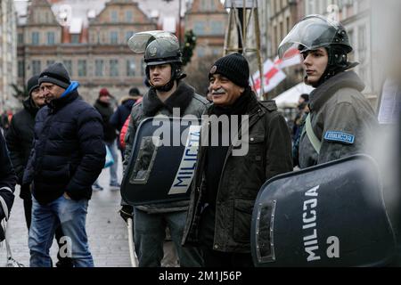 Danzica, Polonia, 11/12/2022, Un uomo si trova vicino a uomini che indossano un'uniforme della milizia della Repubblica popolare Polacca dopo lo spettacolo di strada legato all'anniversario della legge marziale in Polonia, svoltosi in via Dluga nella Città Vecchia. Spettacolo di strada legato all'anniversario della legge marziale in Polonia, tenuto in una delle principali strade turistiche della Città Vecchia. La legge marziale in Polonia esisteva tra il 13 dicembre 1981 e il 22 luglio 1983. Il governo polacco della Repubblica popolare ha introdotto la legge marziale e una giunta militare come tentativo di contrastare il movimento di solidarietà (iniziato a Danzica) e la politica Foto Stock