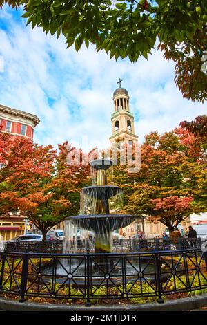 New York City splendida fontana circondata da alberi autunnali con chiesa cristiana campanile dietro Foto Stock