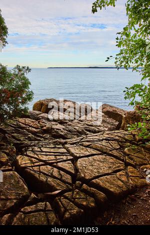 Superficie rocciosa con grandi tagli in tutte le direzioni che si affaccia sul lago nelle giornate nuvolose Foto Stock