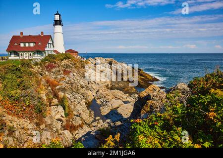 Il classico faro bianco del Maine si affaccia sull'oceano sulle coste rocciose Foto Stock