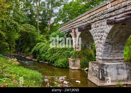 Fiume con enormi archi in pietra del ponte ferroviario che attraversa Foto Stock