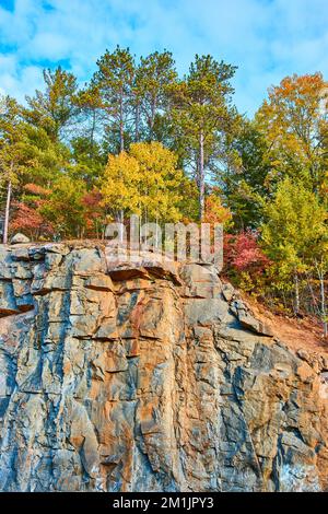 Grande scogliera con colorati alberi a cascata che coprono la cima Foto Stock