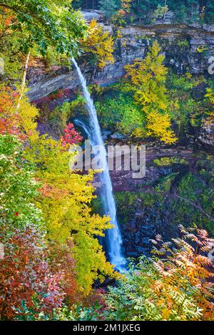 La splendida e alta cascata sulle scogliere è circondata dal colorato fogliame di picco Foto Stock