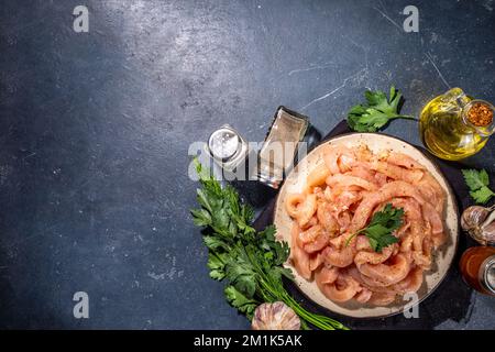 Dieta di cottura sfondo bianco di carne di pollame. Strisce di pollo fresche a fette crude per la cottura, con spezie, erbe aromatiche, su uno sfondo di cemento nero vista dall'alto c Foto Stock